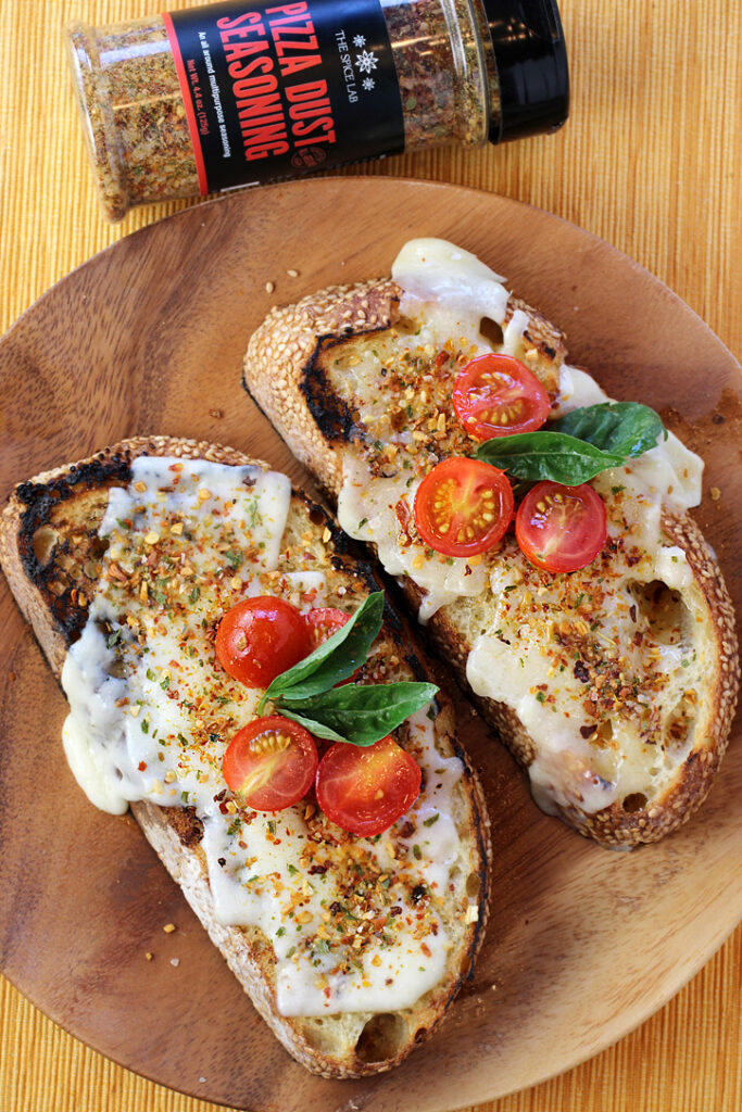 Grilled bread with cheese, tomatoes and basil that gets a generous sprinkling of The Spice Lab's Pizza Dust Seasoning.